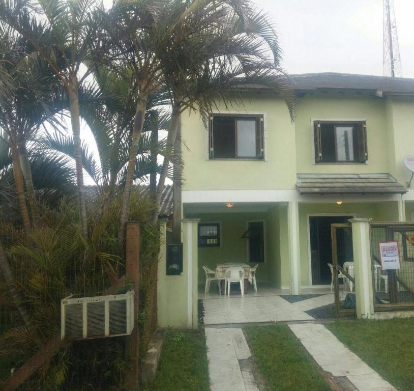 a house with palm trees in front of it at Casa 3 dormitórios in Tramandaí