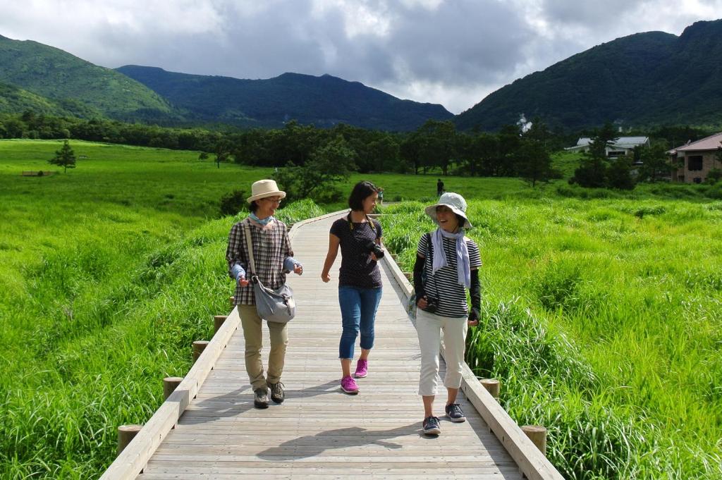 a group of three people walking on a boardwalk at Polan no Fue in Minamioguni