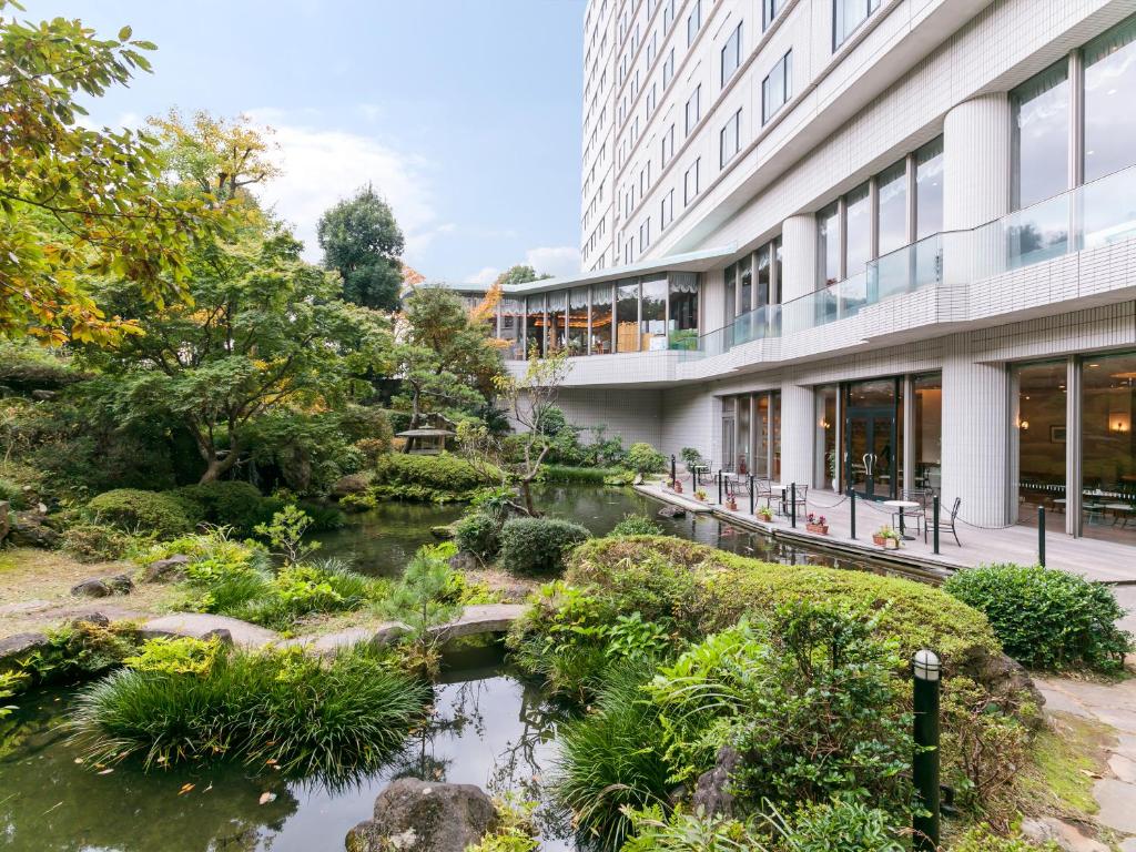 a garden with a river in front of a building at HOTEL MYSTAYS PREMIER Narita in Narita