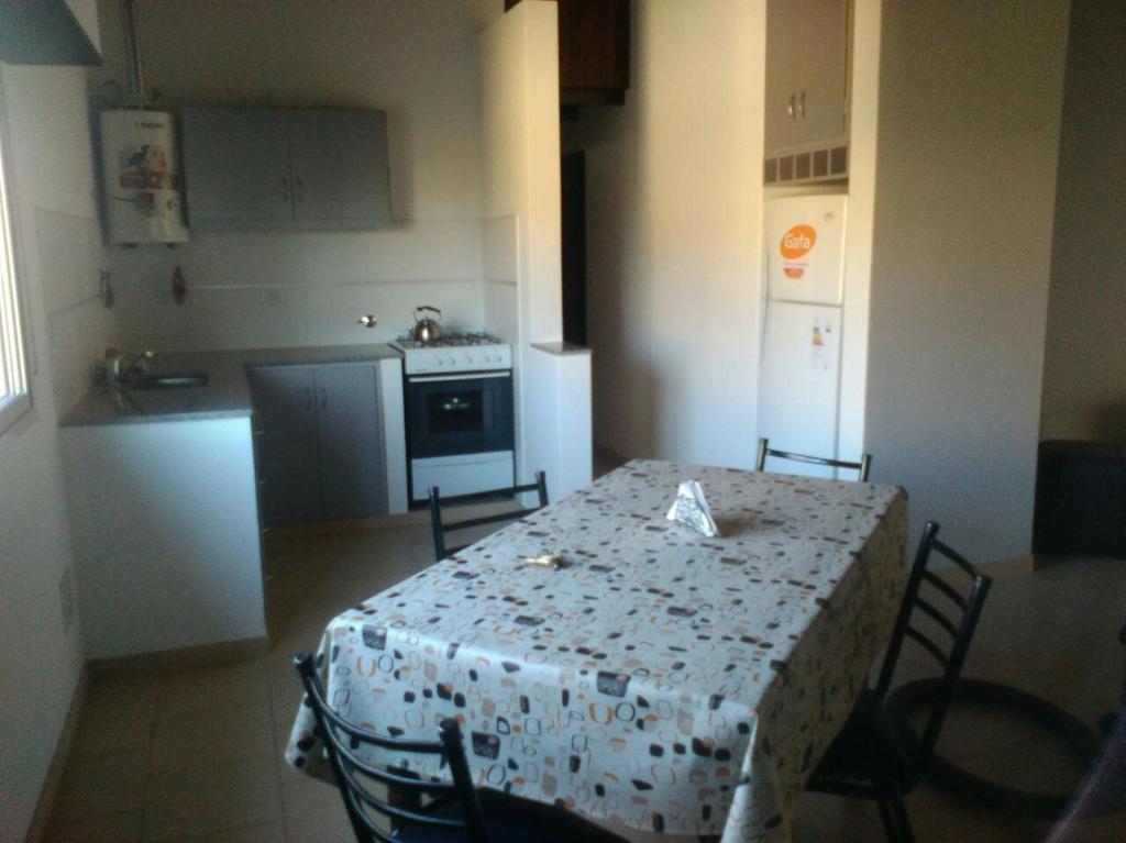 a kitchen with a table and chairs and a kitchen with a stove at Alquileres Pedro in Olavarría