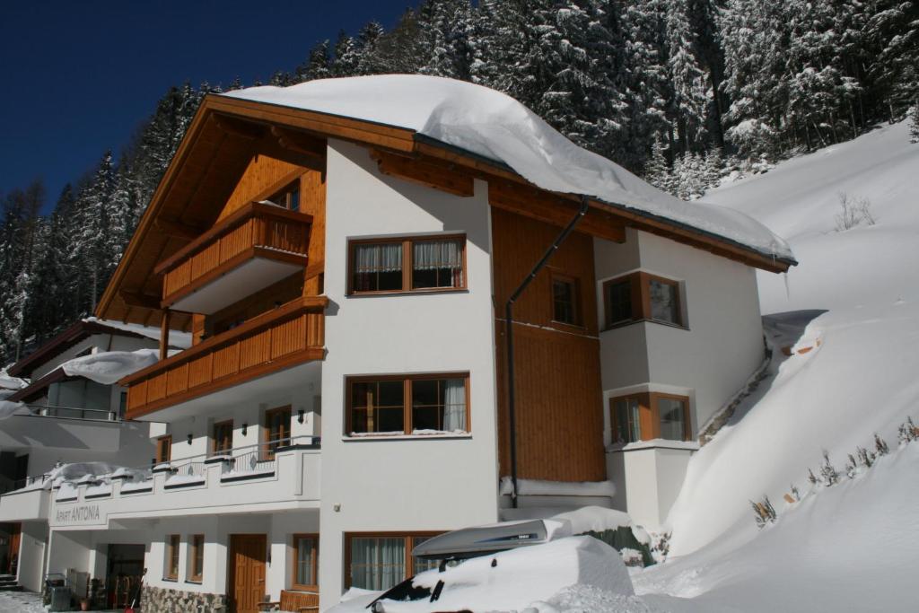 a building in the snow with a car in front at Apart Antonia in Ischgl