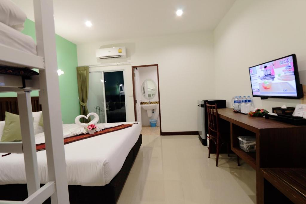 a bedroom with a bed and a desk and a television at BS Airport at Phuket in Nai Yang Beach