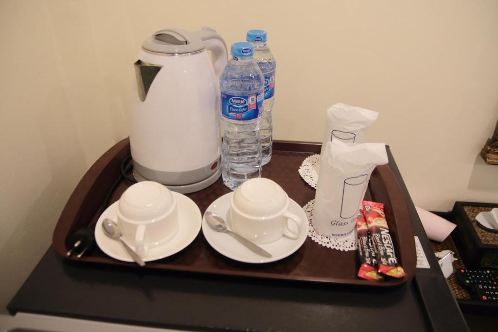 a tray with cups and saucers and a bottle of water at BS Airport at Phuket in Nai Yang Beach