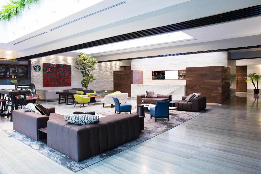 An open lobby lounge with sofas, armchairs, tables, artwork and a café counter.