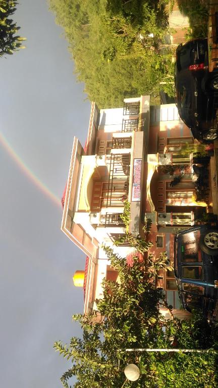 ein Regenbogen über einem Haus mit einem Auto vor dem Haus in der Unterkunft Hotel Edelweis 2 Bajawa in Bajawa