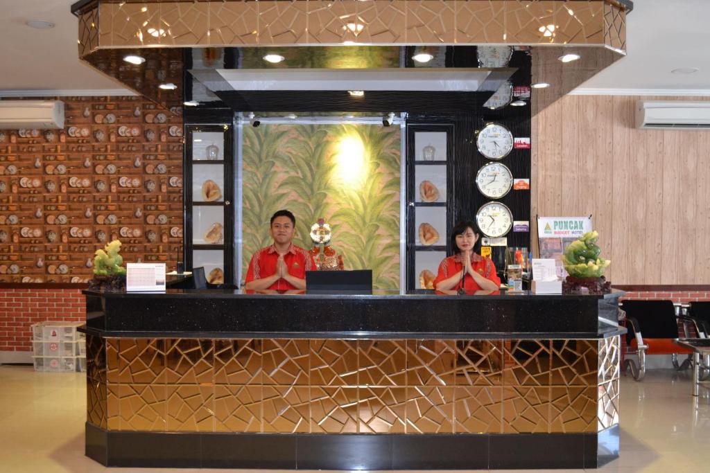 a man and woman standing behind a counter in a restaurant at Puncak Budget Hotel in Pangkalpinang