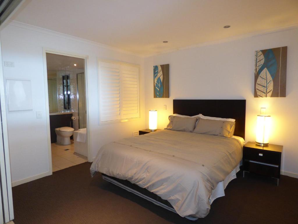 a bedroom with a large bed and two lamps on tables at Marina View Apartment in Airlie Beach