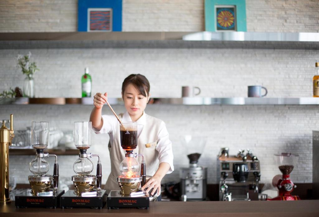 a woman in a kitchen preparing a drink in a blender at Lake Biwa Otsu Prince Hotel in Otsu