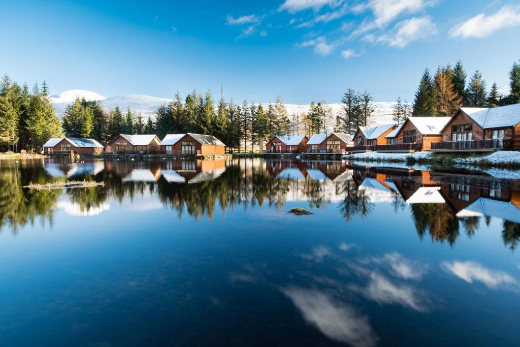 a reflection of houses in a lake with snow at Lodge 9 Glengoulandie Lodges in Aberfeldy