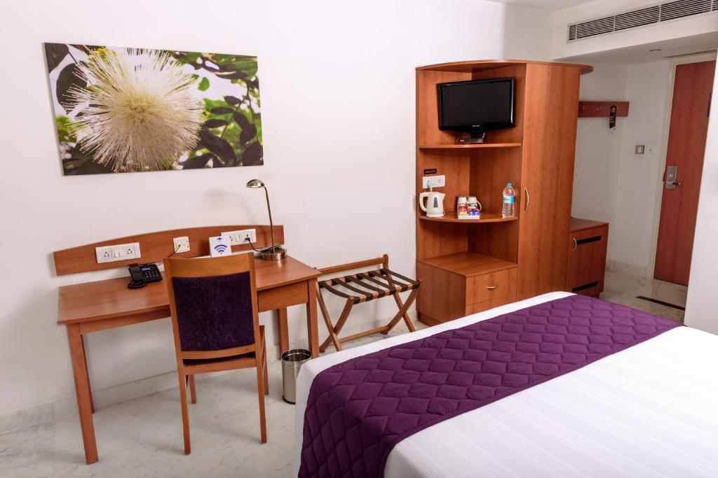 Schlafzimmer mit einem Bett, einem Schreibtisch und einem Computer in der Unterkunft Caspia Hotel New Delhi in Neu-Delhi