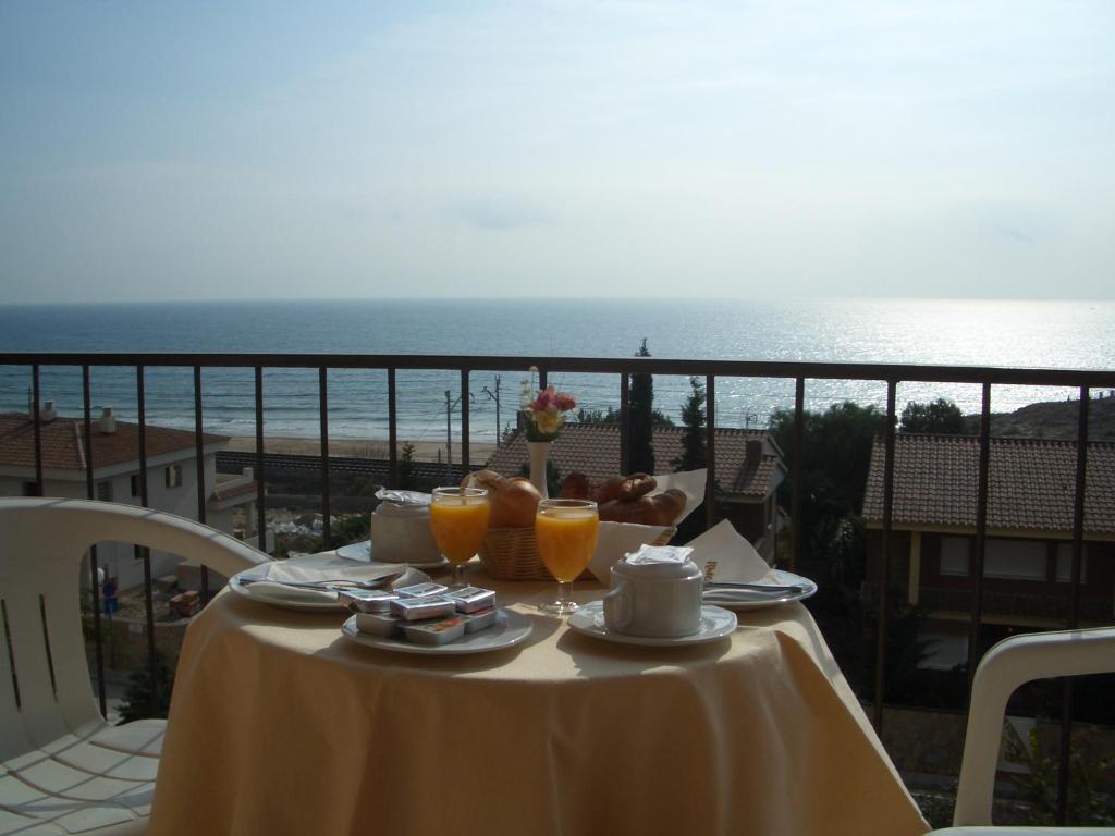 uma mesa com comida e bebidas numa varanda com o oceano em Hotel Sant Jordi em Tarragona