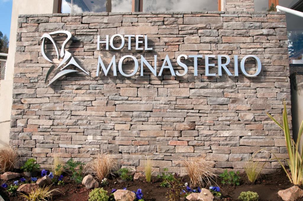 a sign for a hotel monasterio on a brick wall at Monasterio Hotel Boutique in San Carlos de Bariloche