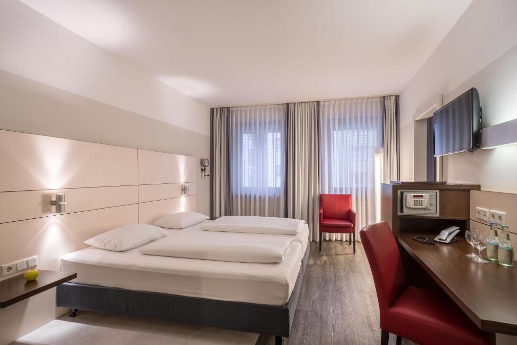 um quarto de hotel com uma cama e uma cadeira vermelha em Ferrotel Duisburg - Partner of SORAT Hotels em Duisburg