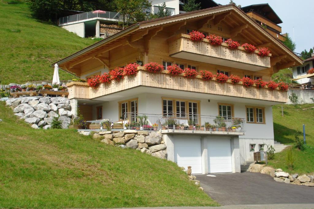 a house with a balcony with red flowers on it at Oeystrasse 10a in Adelboden