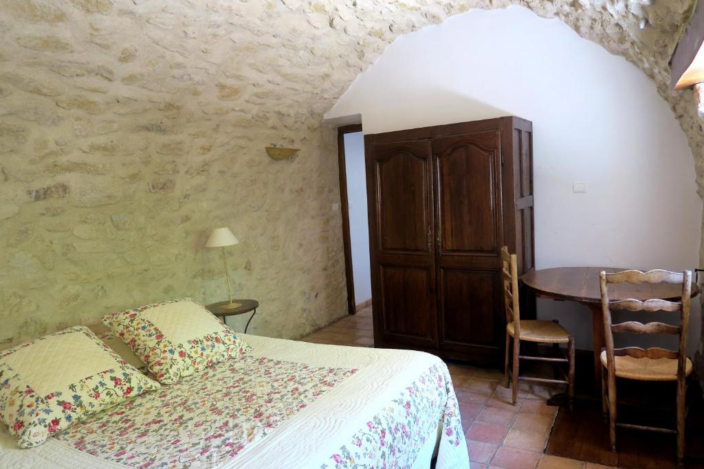 een slaapkamer met een bed en een tafel bij Le Bastidon - La Luberonne in Lourmarin