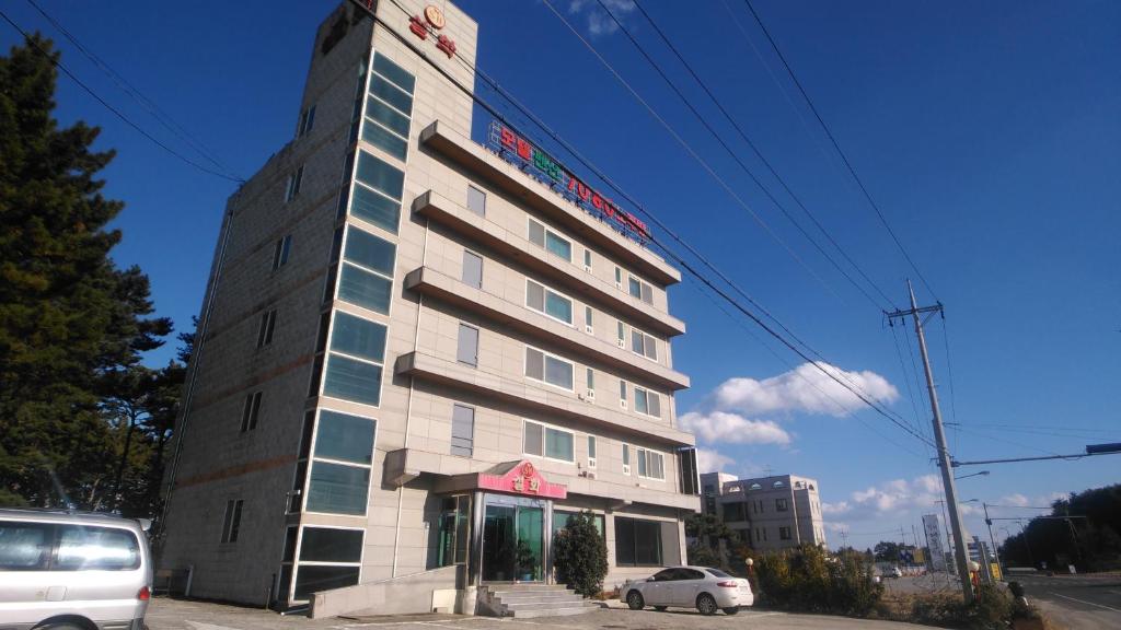 ein hohes Gebäude mit einem davor geparkt in der Unterkunft Seolhwa Motel in Yangyang