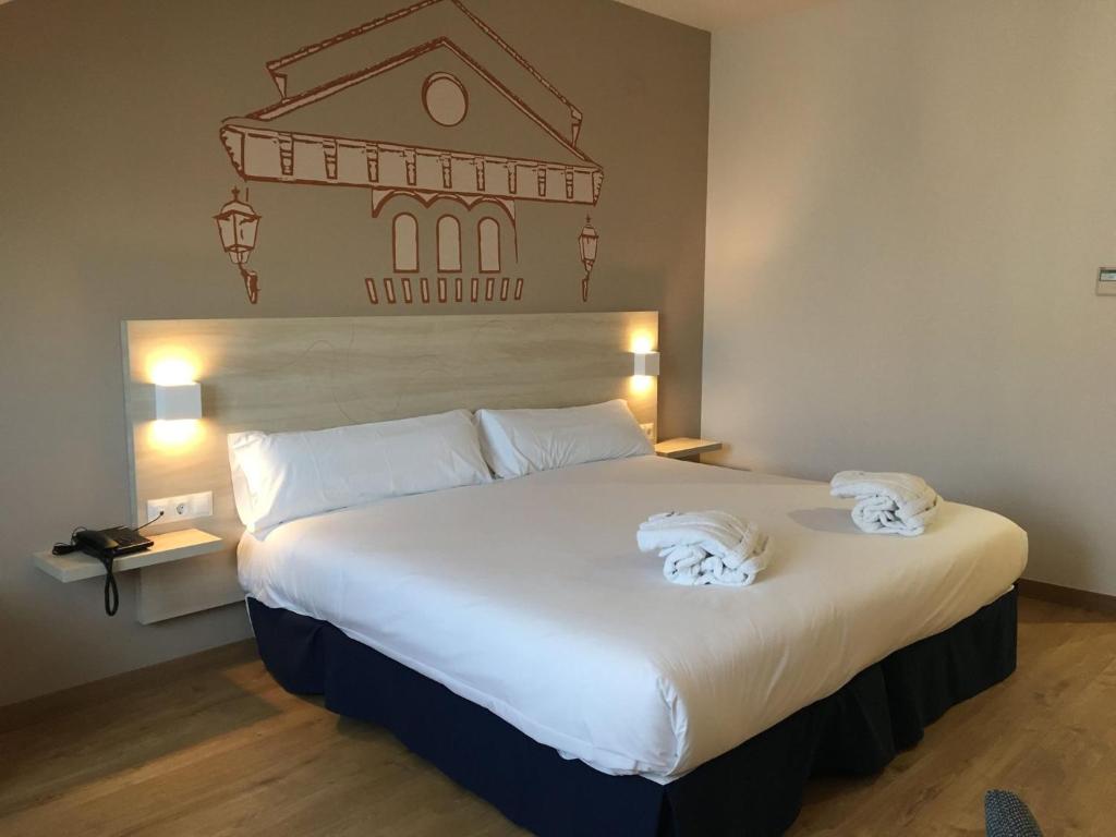 1 dormitorio con 1 cama blanca grande y toallas. en Hotel Balneario de Graena en Graena