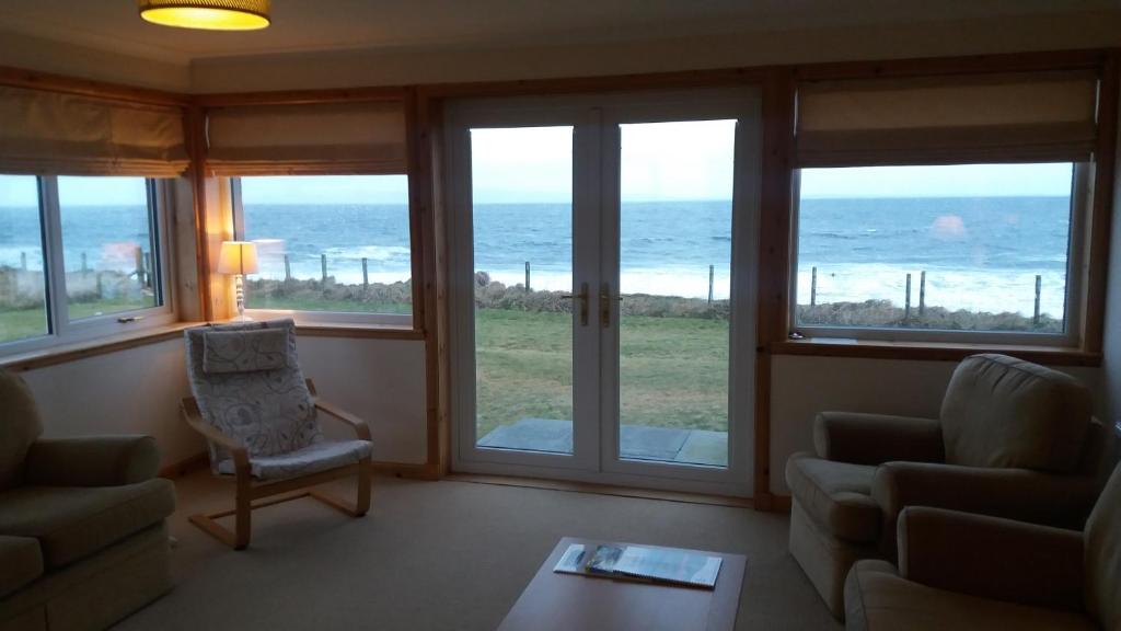 a living room with a view of the ocean at Mey Cliff Cottage in Scarfskerry