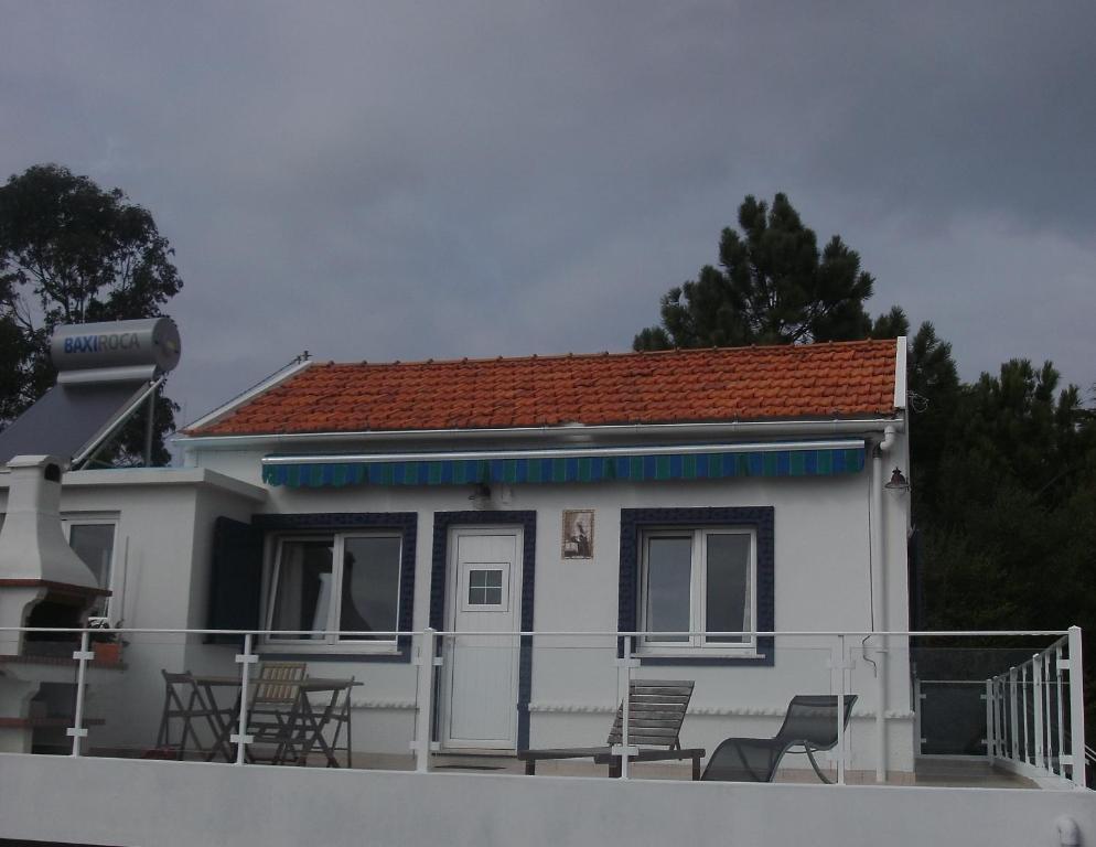 a small white house with chairs on a balcony at Casa das conchas in Buarcos