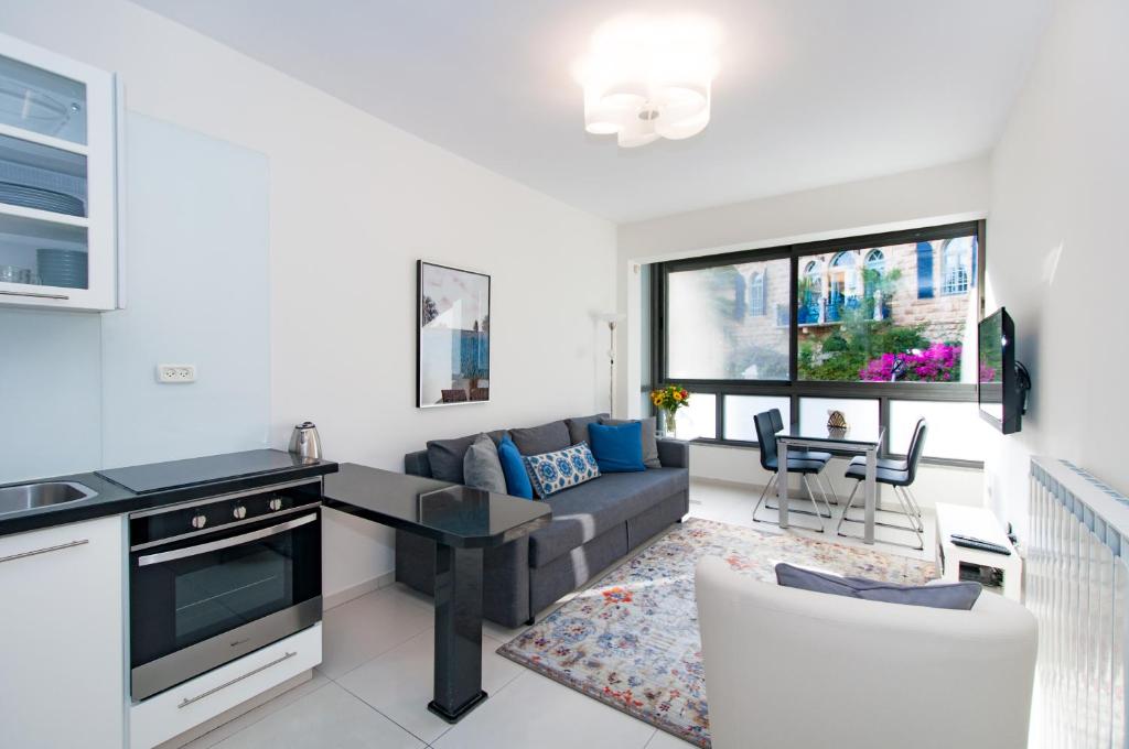 a kitchen and living room with a couch and a table at Colony Suites - Hildesheimer St. in Jerusalem