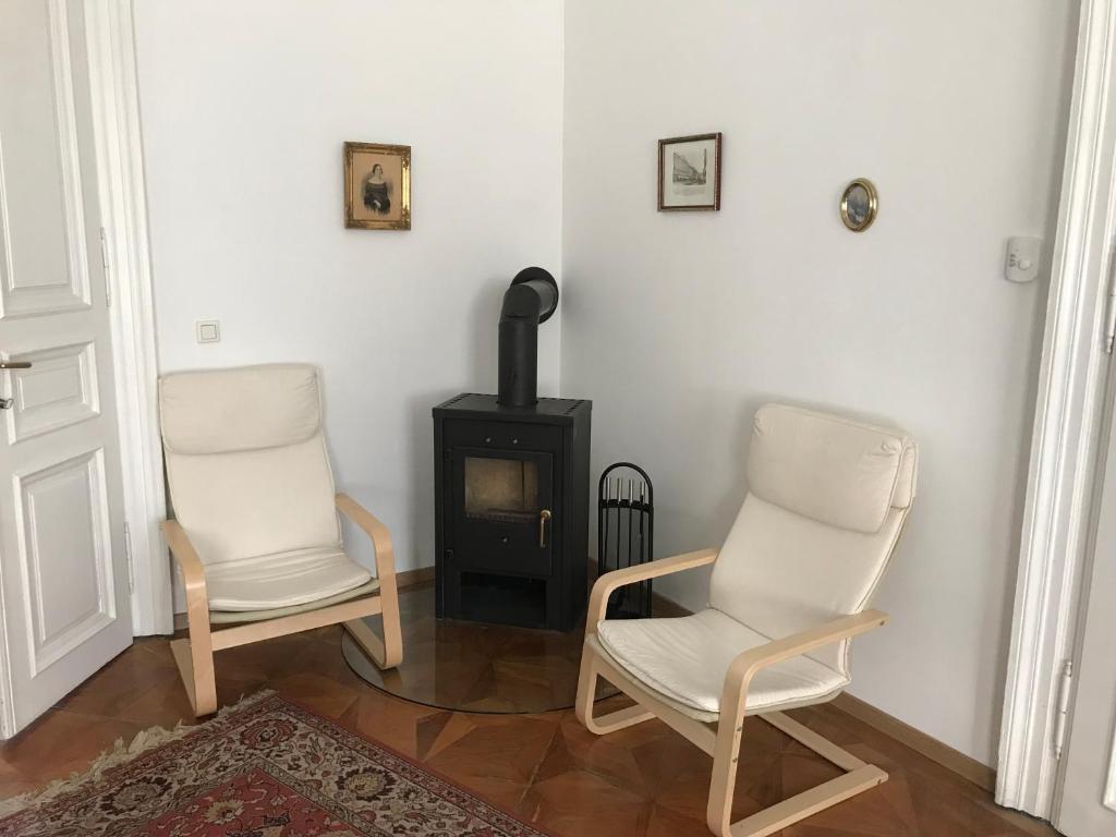 two white chairs in a room with a stove at 88m² großes Apartment im 1. Stock in Vienna
