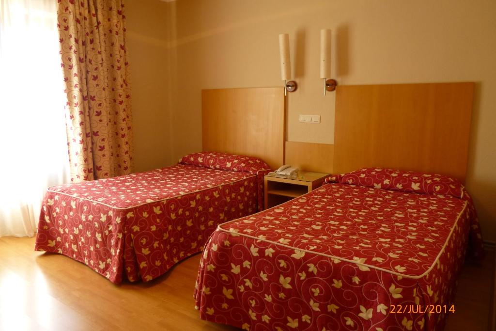 2 camas en una habitación de hotel con colchas rojas en Hotel Alisa, en Lerma