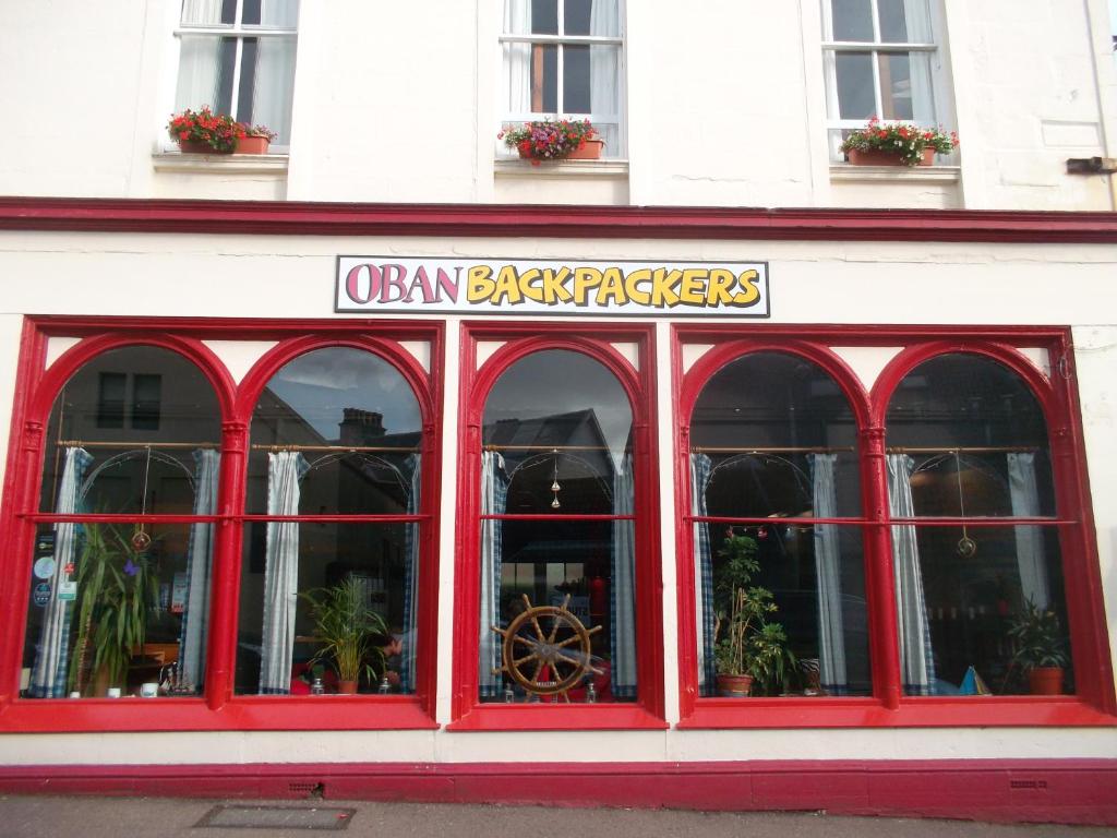 un restaurante con ventanas rojas y un cartel en él en Oban Backpackers, en Oban