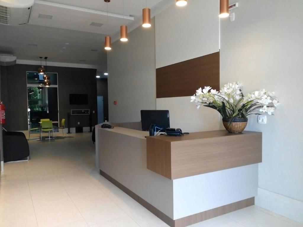 an office lobby with a reception desk with flowers on it at Brito Hotel in Resplendor