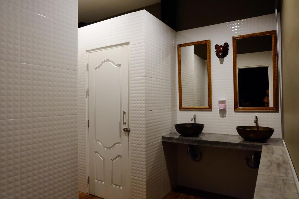 a bathroom with two sinks and two mirrors at Bloom Cafe & Hostel in Ko Lipe
