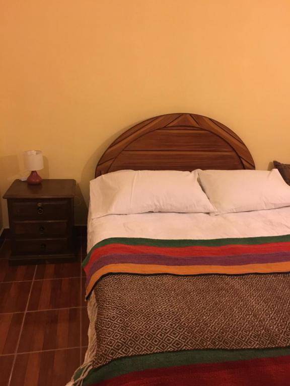 a bed with a wooden headboard and a night stand at Lodge Andino Lamphaya in Sol de la Mañana