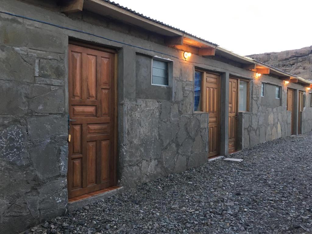 una fila de puertas de madera en un edificio de piedra en Lodge Andino Lamphaya en Sol de la Mañana