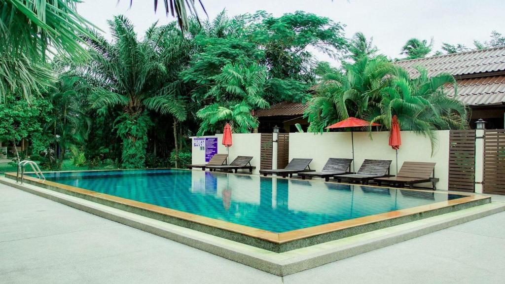 una piscina in un resort con sedie e alberi di Palm Sweet Resort a Chumphon