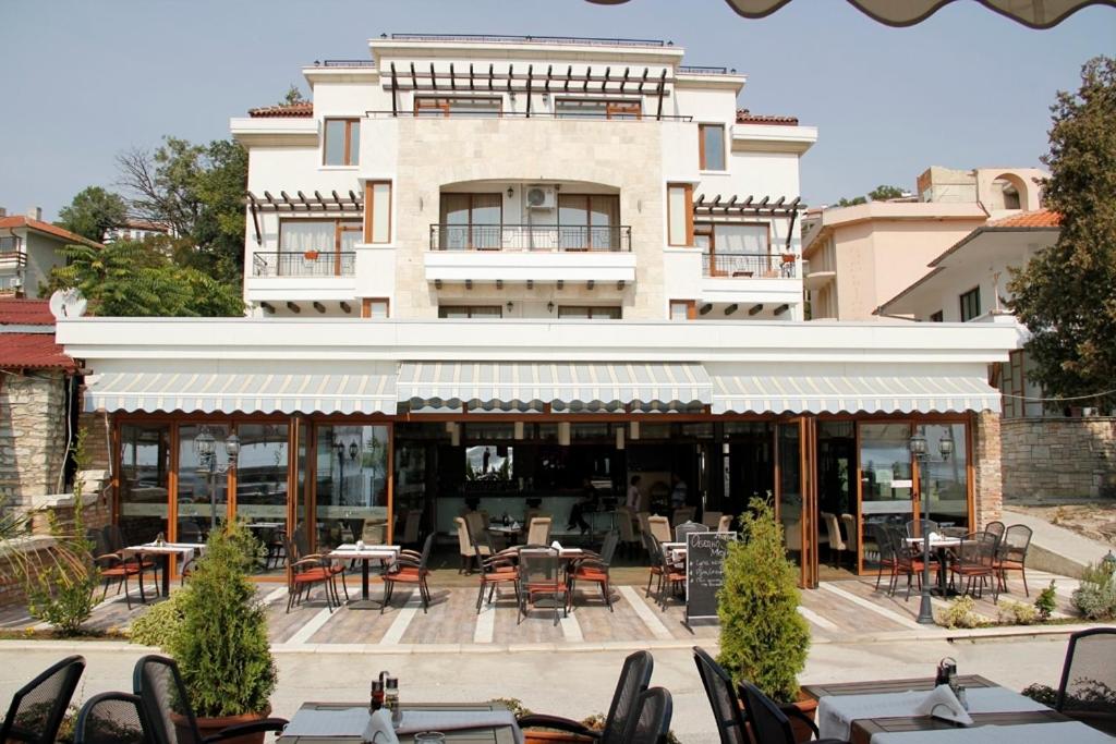 um restaurante com mesas e cadeiras em frente a um edifício em Selena Hotel em Balchik