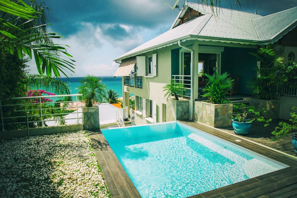 a house with a swimming pool next to the ocean at Alyzes Diamant in Le Diamant