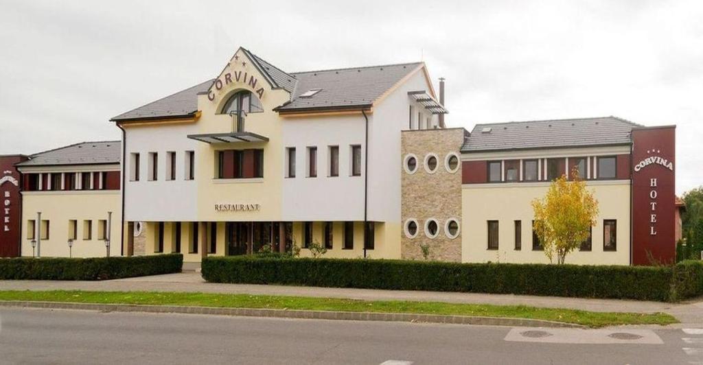 a large white building on the side of a street at Corvina Hotel-Restaurant in Mosonmagyaróvár