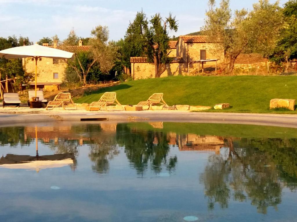 um grupo de cadeiras sentadas ao lado de um lago em Agriturismo Le Canterie em Radicondoli