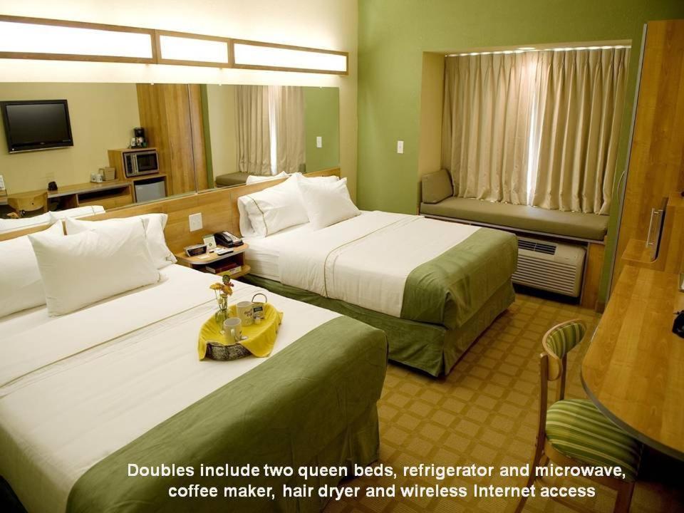 a hotel room with two beds and a yellow suitcase at Microtel Inn & Suites by Wyndham Saraland in Saraland