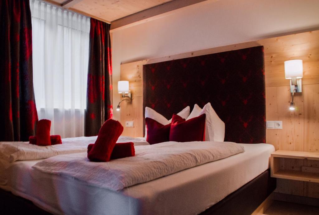 a hotel room with a large bed with red chairs at Piburg Studios in Oetz