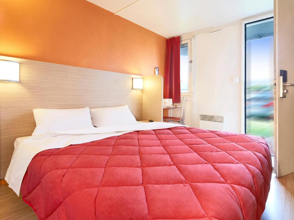 a large red bed in a room with a window at Premiere Classe Plaisir in Plaisir