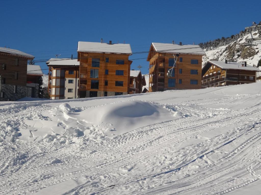 a snow covered slope with buildings in the background at Alpenresort B22 in Riederalp