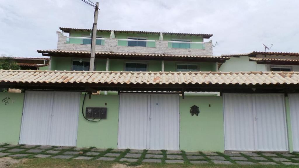 una casa verde con puertas blancas de garaje delante de ella en Triplex, Cabo Frio, Praia do Peró, en Cabo Frío