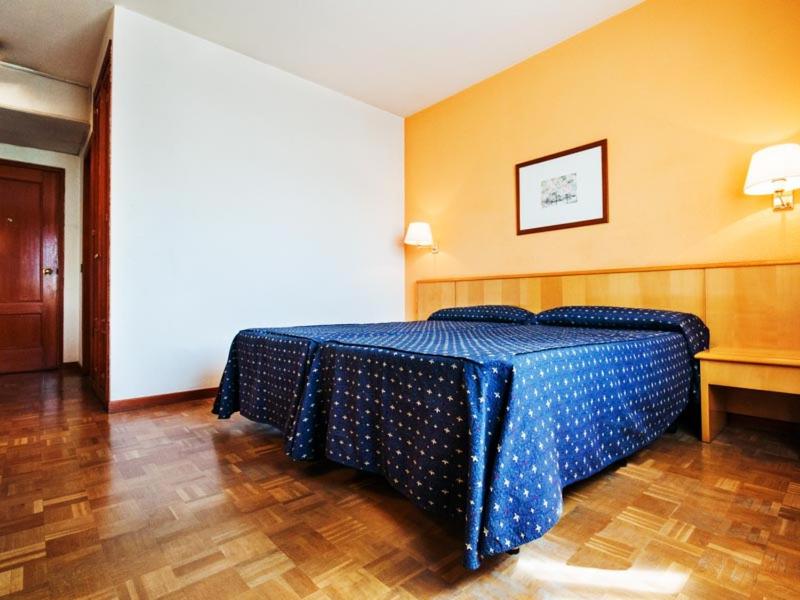 a bedroom with a bed with a blue comforter at Hotel Alcarria in Guadalajara