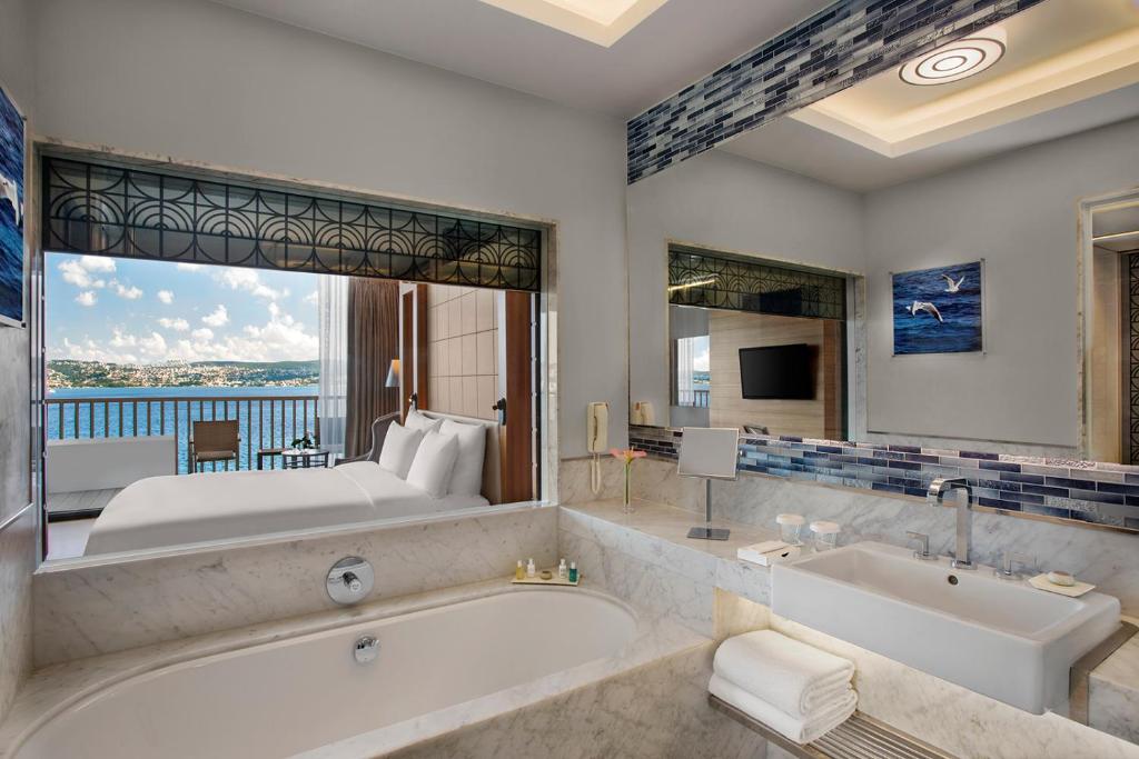 a bathroom with a tub and a bedroom with a bed at The Grand Tarabya Managed by Accor in Istanbul
