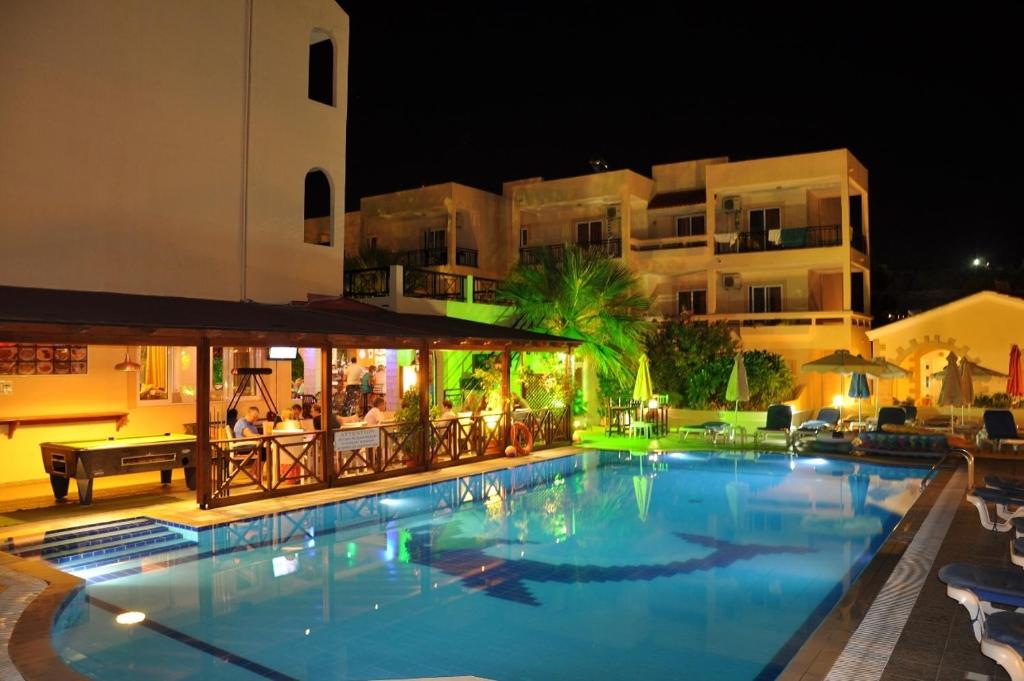 a large swimming pool in front of a building at night at Summer Memories Aparthotel in Pefki Rhodes