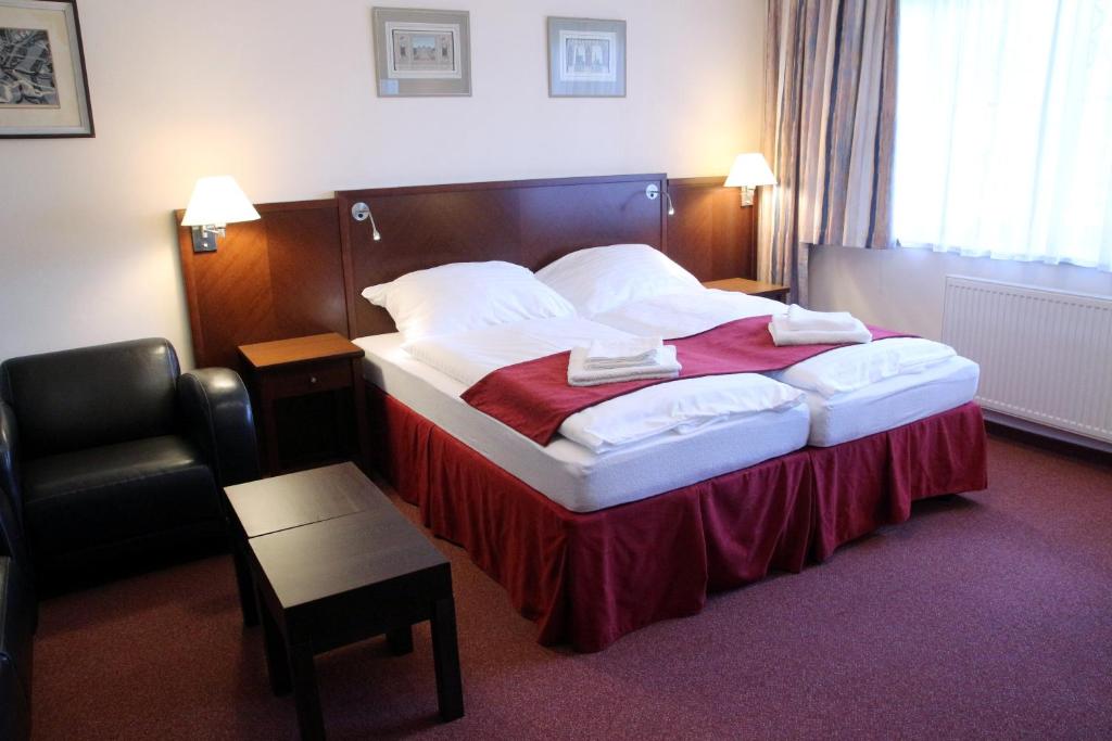 a hotel room with a bed and a chair at Apartment Hanspaulka Garden in Prague