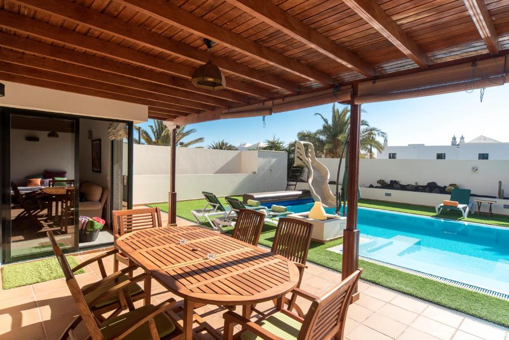 een patio met een tafel en stoelen en een zwembad bij Arpaso in Costa Teguise