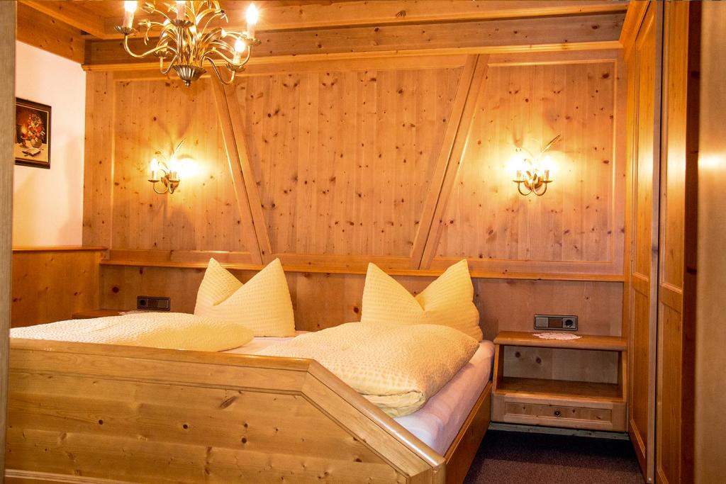 a bed with white pillows in a room with wooden walls at Apart Piz Palü Kappl/Ischgl in Kappl