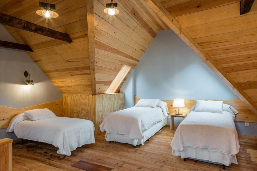 2 łóżka w pokoju na poddaszu z drewnianymi sufitami w obiekcie Casa Rural "Casa Chin", Val d'Aran w mieście Betrén