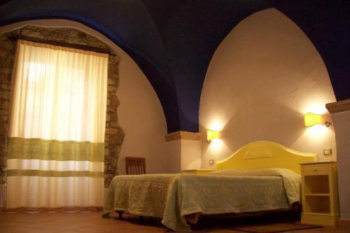 1 dormitorio con cama y ventana con cortina en Sa Balza Guest House, en Bosa