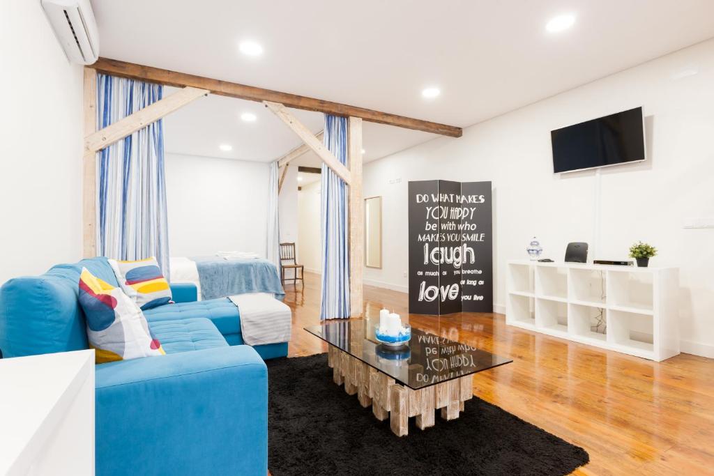 ein Wohnzimmer mit einem blauen Sofa und einem Tisch in der Unterkunft FLH Graça Artistic Studio in Lissabon